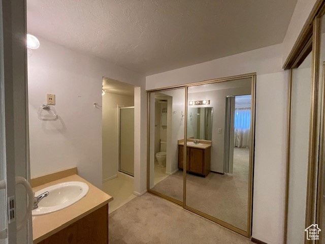 Bathroom with vanity, toilet, walk in shower, and a textured ceiling