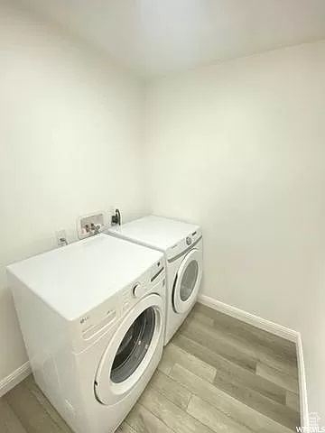 Clothes washing area featuring light hardwood / wood-style flooring, washer and clothes dryer, and washer hookup