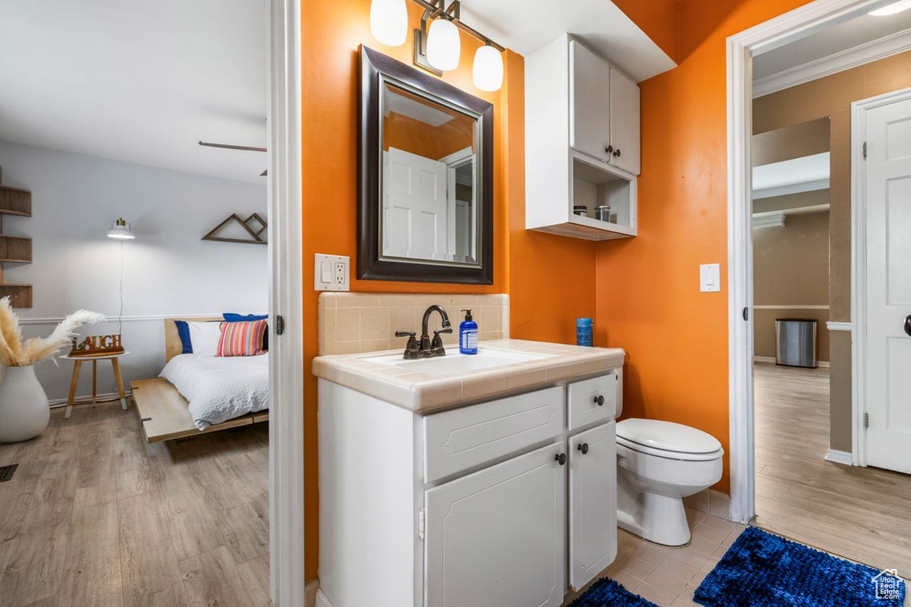 Bathroom with vanity, toilet, tasteful backsplash, and hardwood / wood-style floors
