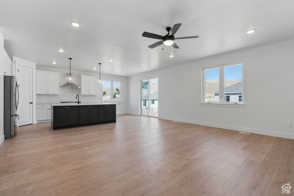 Unfurnished living room featuring sink, light hardwood / wood-style flooring, and ceiling fan
