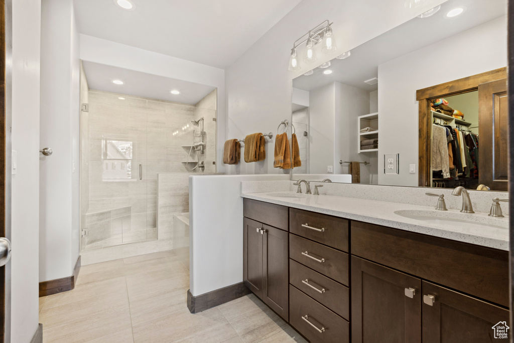 Bathroom with a tile shower, tile flooring, double sink, and vanity with extensive cabinet space