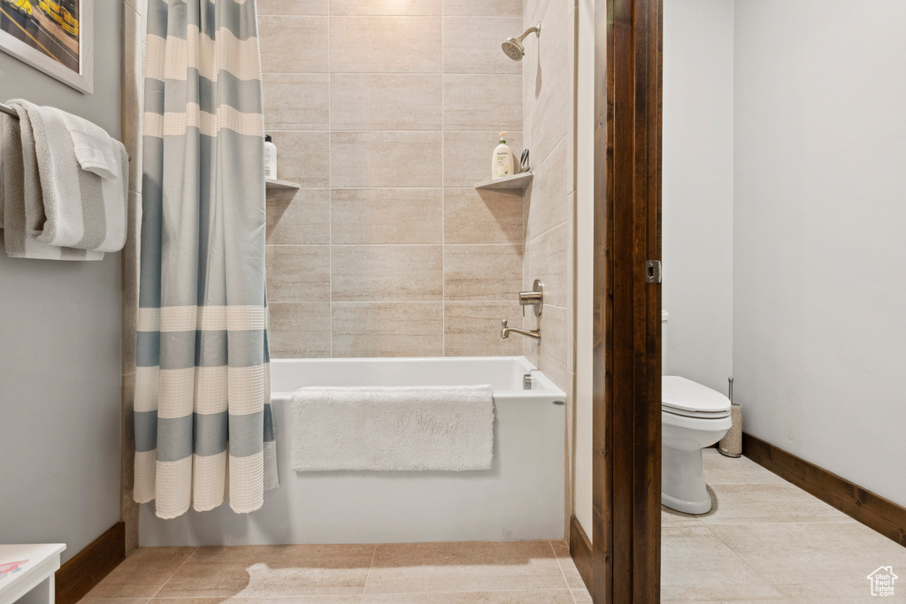 Bathroom with shower / bathtub combination with curtain, toilet, and tile floors