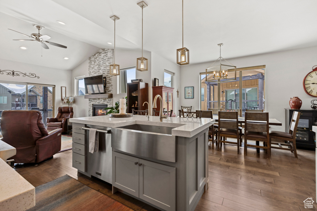 Kitchen featuring ceiling fan with notable chandelier, dark hardwood / wood-style floors, a stone fireplace, gray cabinets, and hanging light fixtures