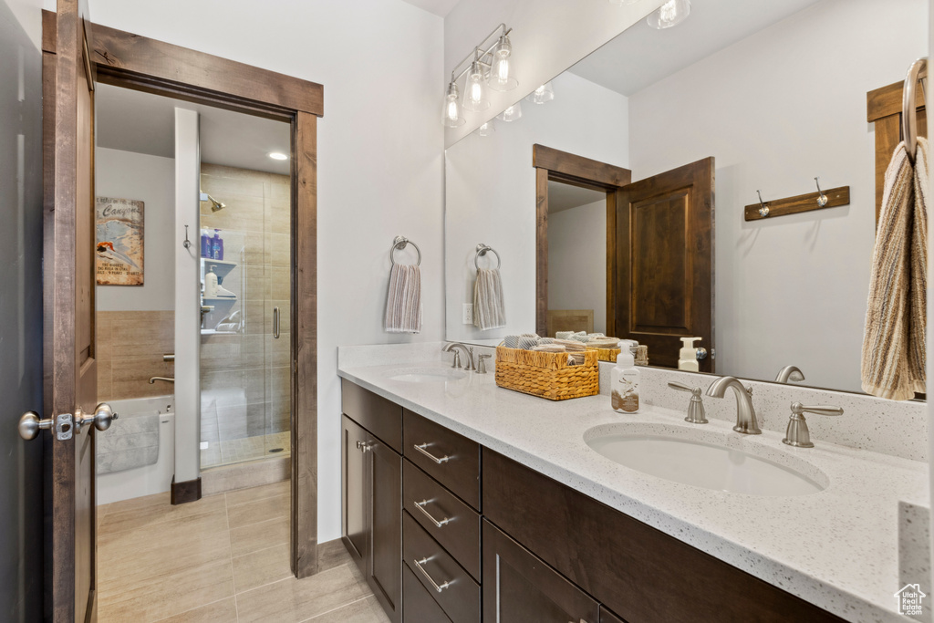 Bathroom with an enclosed shower, dual sinks, vanity with extensive cabinet space, and tile floors