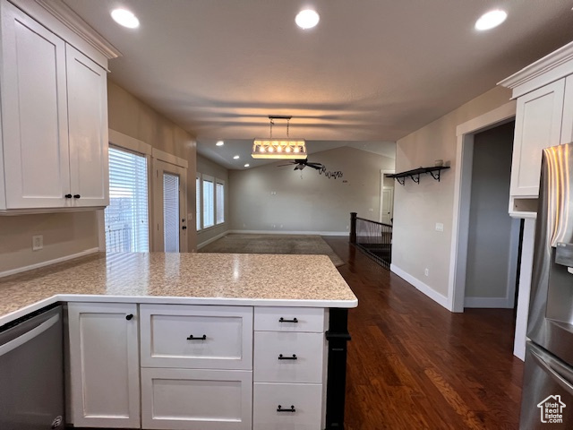 Kitchen with dark hardwood / wood-style flooring, decorative light fixtures, appliances with stainless steel finishes, white cabinetry, and kitchen peninsula