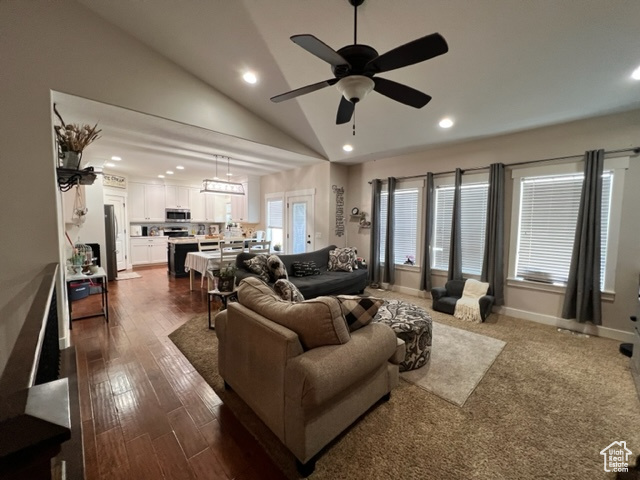 Living room with dark hardwood flooring, vaulted ceiling high, and ceiling fan