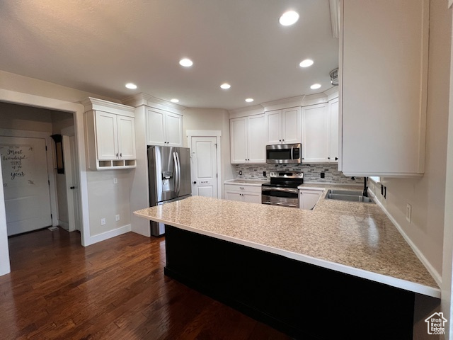 Kitchen featuring dark hardwood / wood-style flooring, sink, appliances with stainless steel finishes, backsplash, and white cabinetry