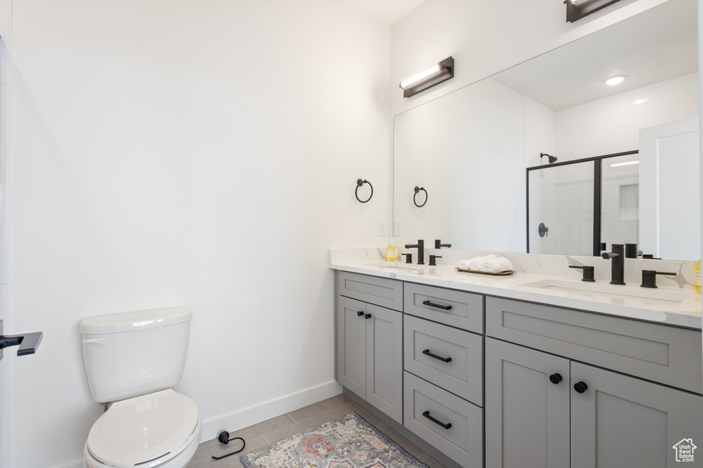 Bathroom with toilet, dual sinks, vanity with extensive cabinet space, and tile flooring