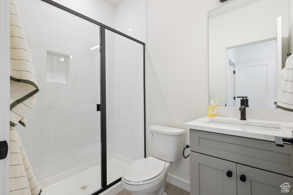 Bathroom featuring vanity with extensive cabinet space, walk in shower, and toilet