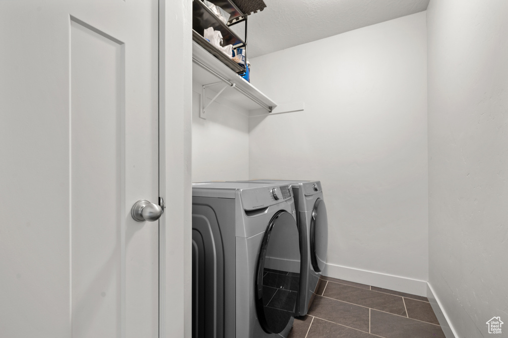Clothes washing area with washing machine and dryer and dark tile flooring