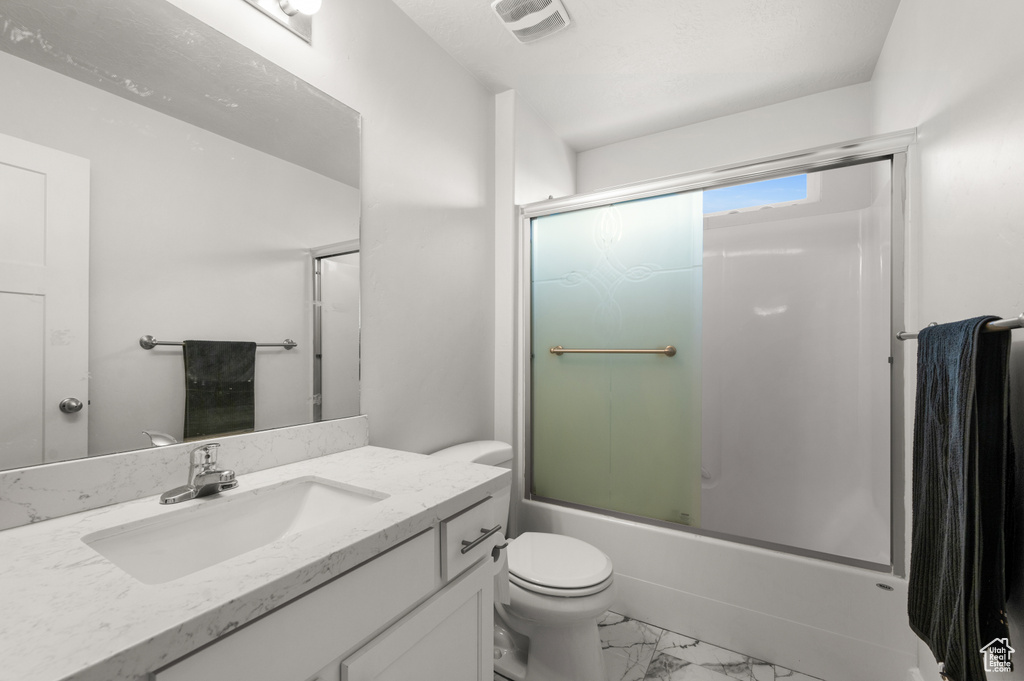 Full bathroom with vanity, enclosed tub / shower combo, tile flooring, and toilet