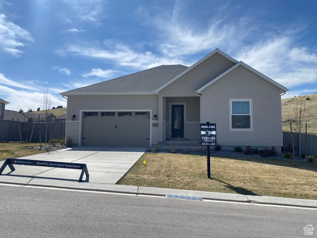 Single story home with concrete driveway, a front lawn, fence, and an attached garage