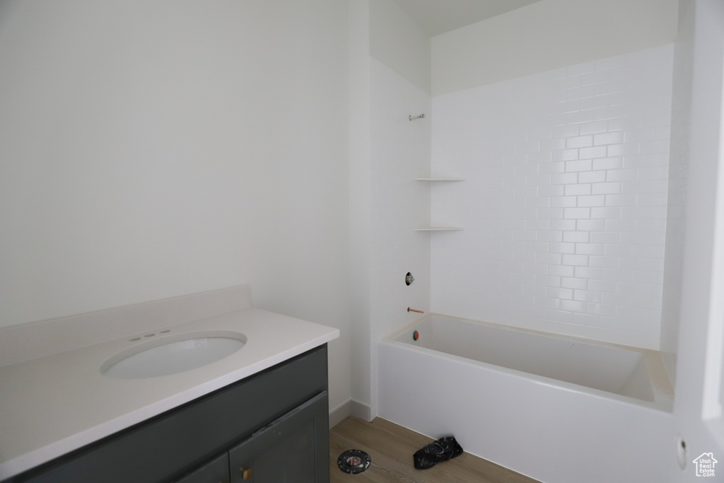 Bathroom featuring washtub / shower combination, vanity, and hardwood / wood-style flooring
