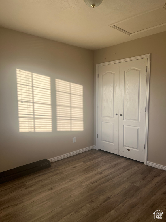 Unfurnished bedroom with a closet and dark hardwood / wood-style floors