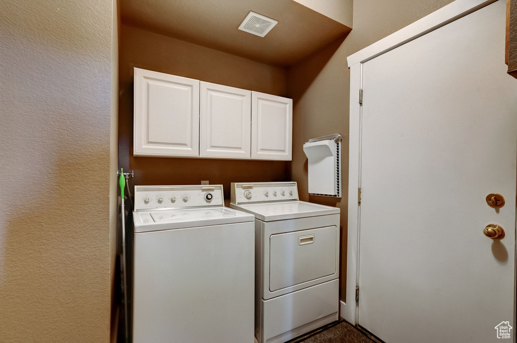 Washroom featuring cabinets and washing machine and clothes dryer