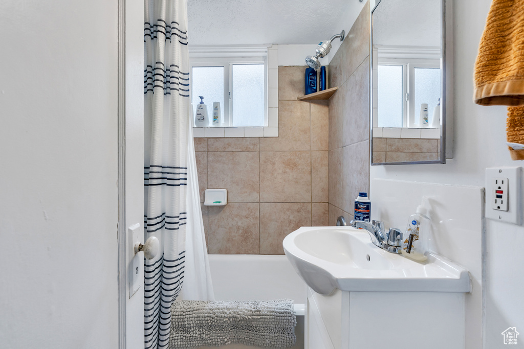 Bathroom with vanity, a healthy amount of sunlight, and shower / bathtub combination with curtain