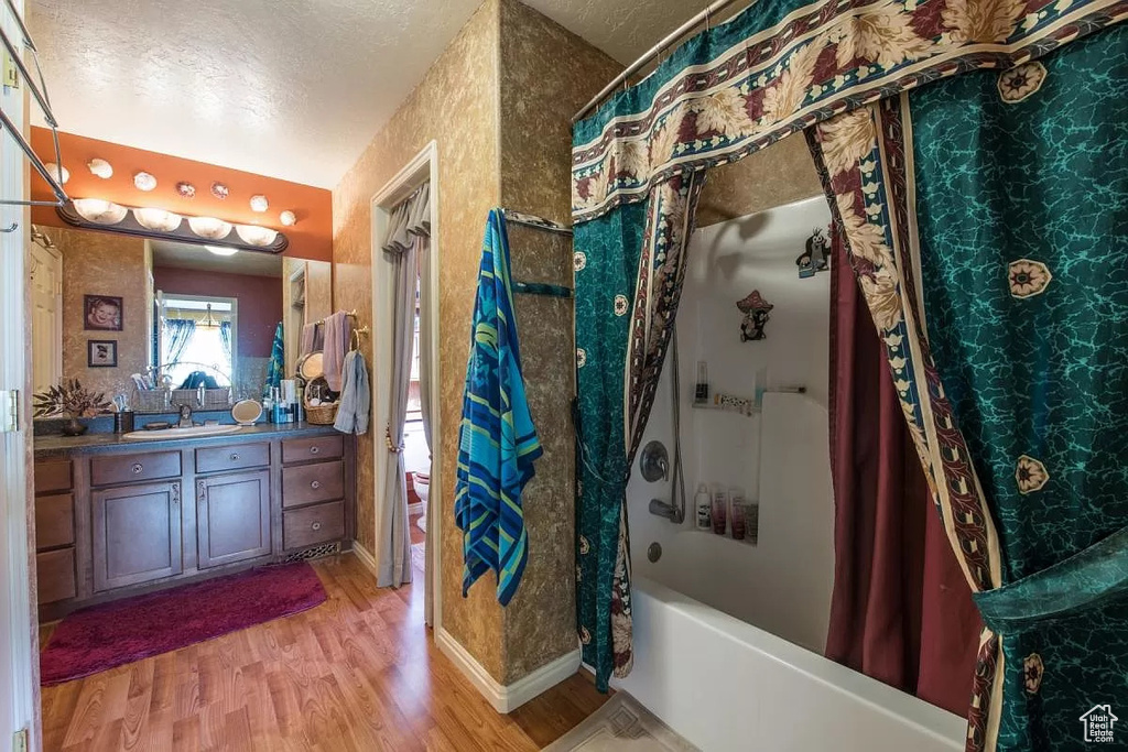Bathroom featuring shower / bathtub combination with curtain, vanity, a textured ceiling, and hardwood / wood-style floors