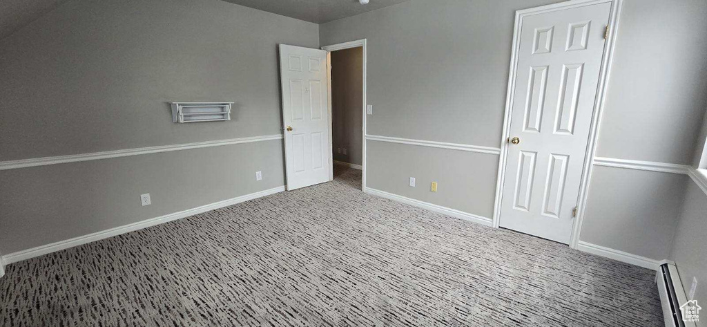 Unfurnished bedroom featuring light carpet and a baseboard radiator
