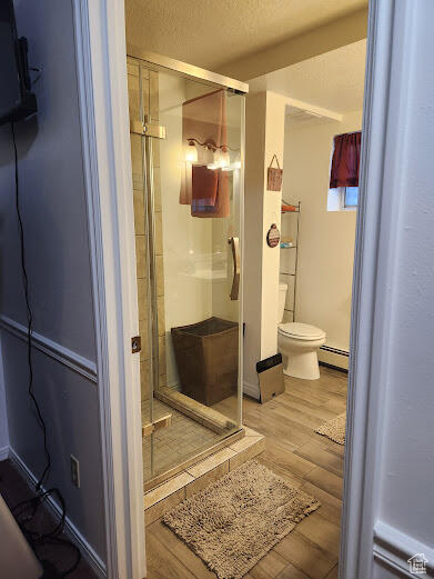 Bathroom with a baseboard heating unit, hardwood / wood-style floors, toilet, and walk in shower