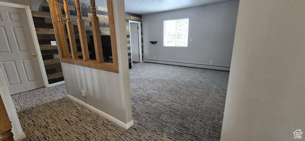 Interior space with a baseboard heating unit and light colored carpet