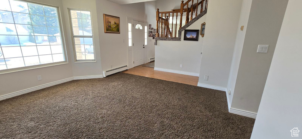 Foyer with light colored carpet and baseboard heating