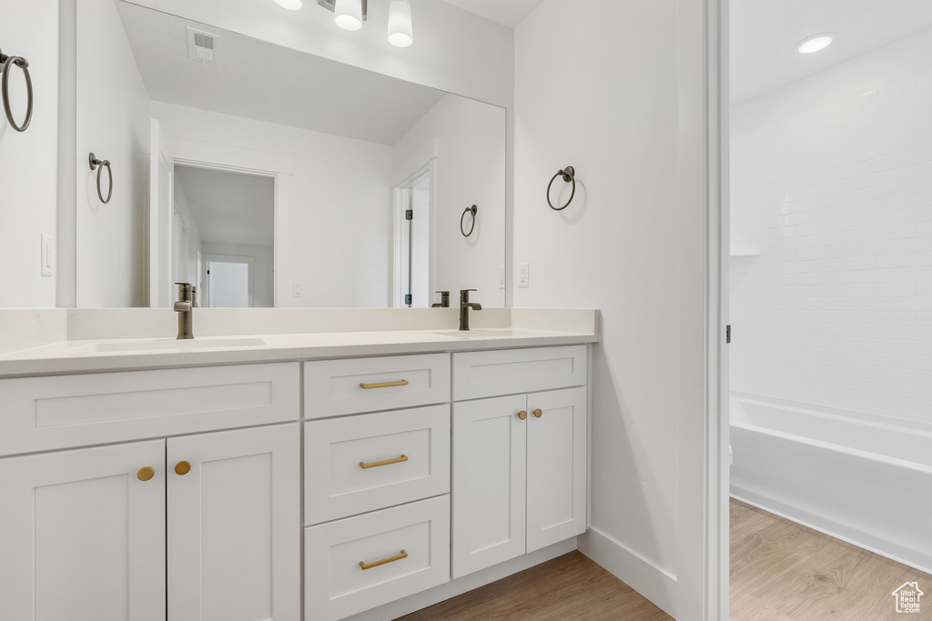 Bathroom featuring shower / bathing tub combination, double sink vanity, and hardwood / wood-style floors