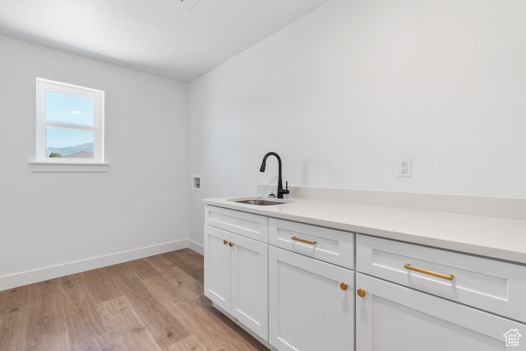 Laundry area featuring cabinets, sink, light hardwood / wood-style flooring, and hookup for a washing machine