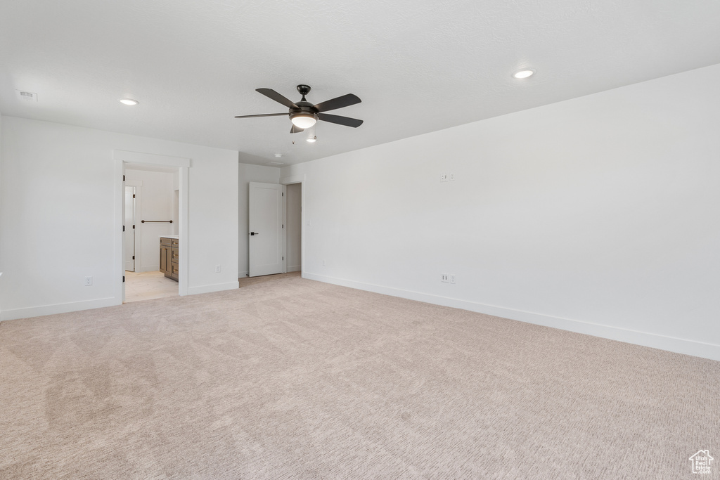 Unfurnished bedroom featuring light carpet, ensuite bath, and ceiling fan