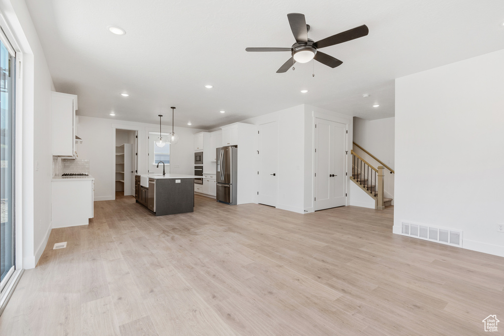 Unfurnished living room with sink, light wood-type flooring, and ceiling fan