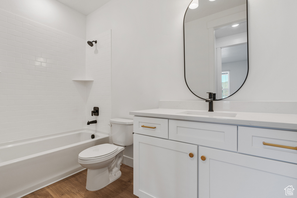 Full bathroom with vanity, toilet, washtub / shower combination, and hardwood / wood-style floors