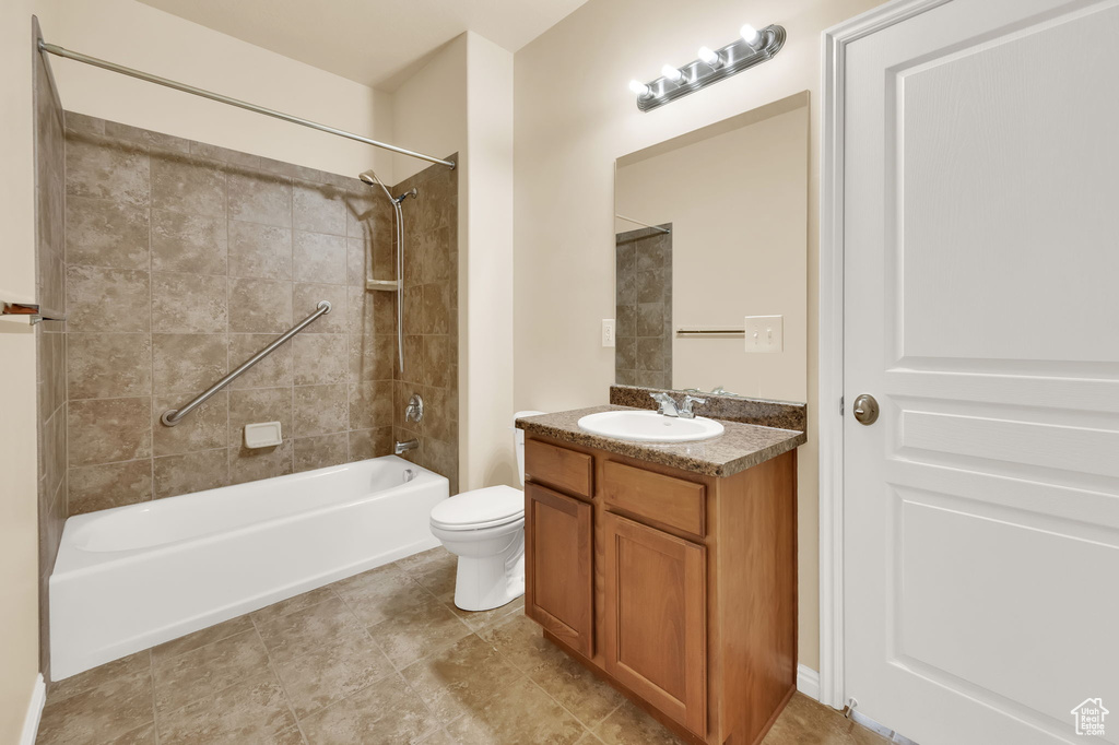 Full bathroom featuring toilet, vanity with extensive cabinet space, tile flooring, and tiled shower / bath