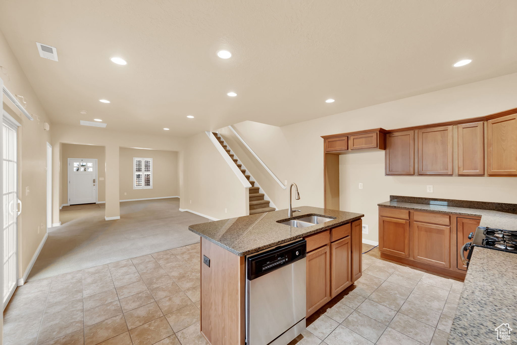 Kitchen featuring light carpet, stainless steel dishwasher, a kitchen island with sink, a wealth of natural light, and sink