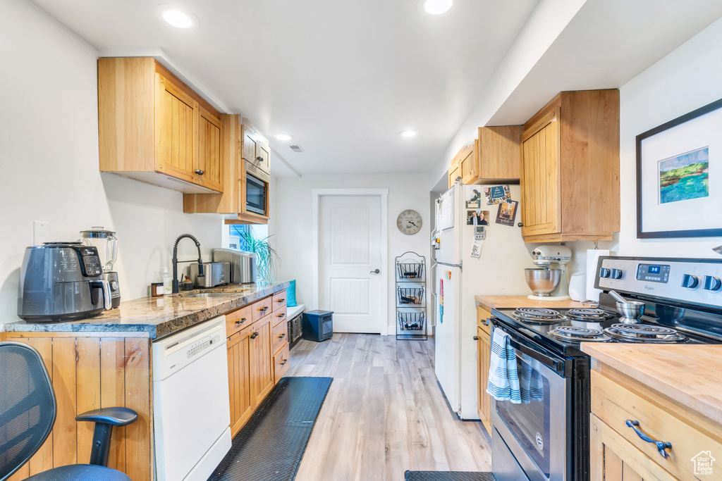 Kitchen with appliances with stainless steel finishes, light wood-type flooring, and sink