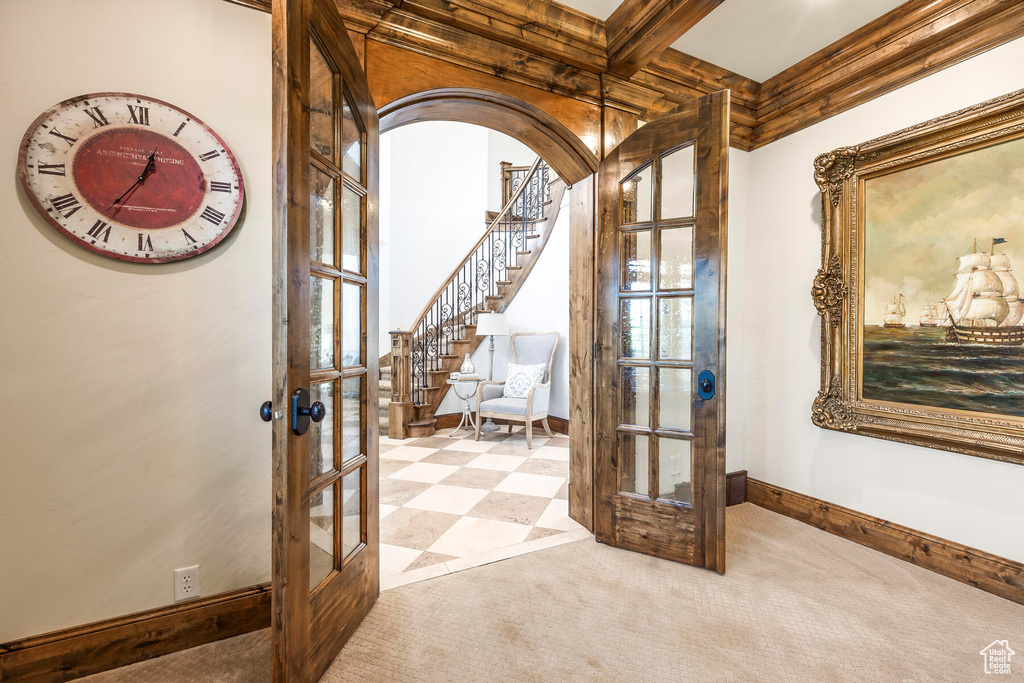 Carpeted foyer entrance with coffered ceiling, french doors, and beamed ceiling