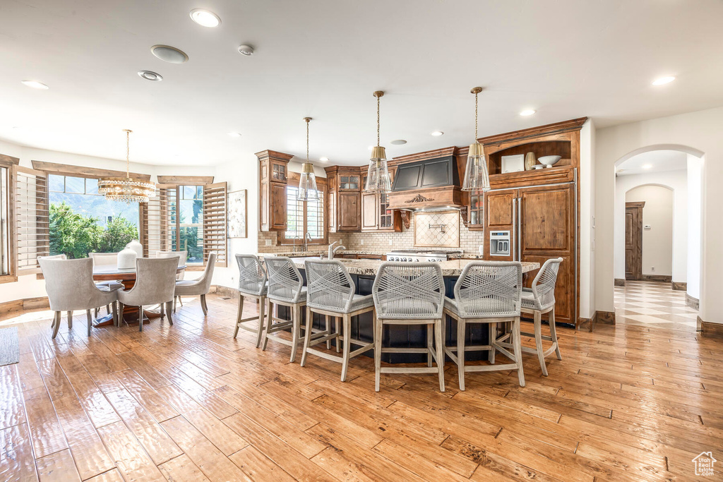 Kitchen with custom exhaust hood, tasteful backsplash, light hardwood / wood-style floors, and a wealth of natural light