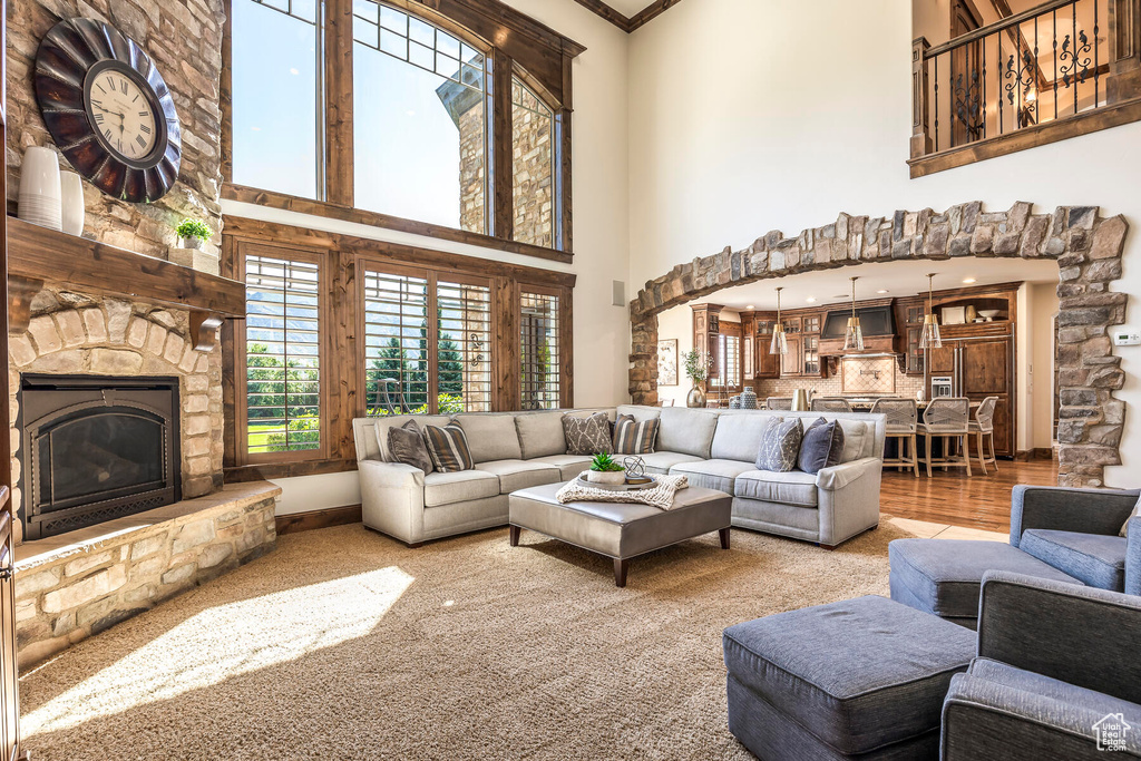 Living room with a fireplace, crown molding, hardwood / wood-style floors, and a towering ceiling