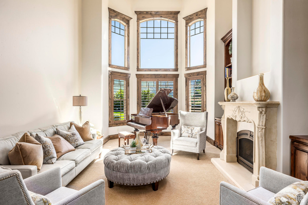 Carpeted living room featuring a fireplace and a towering ceiling