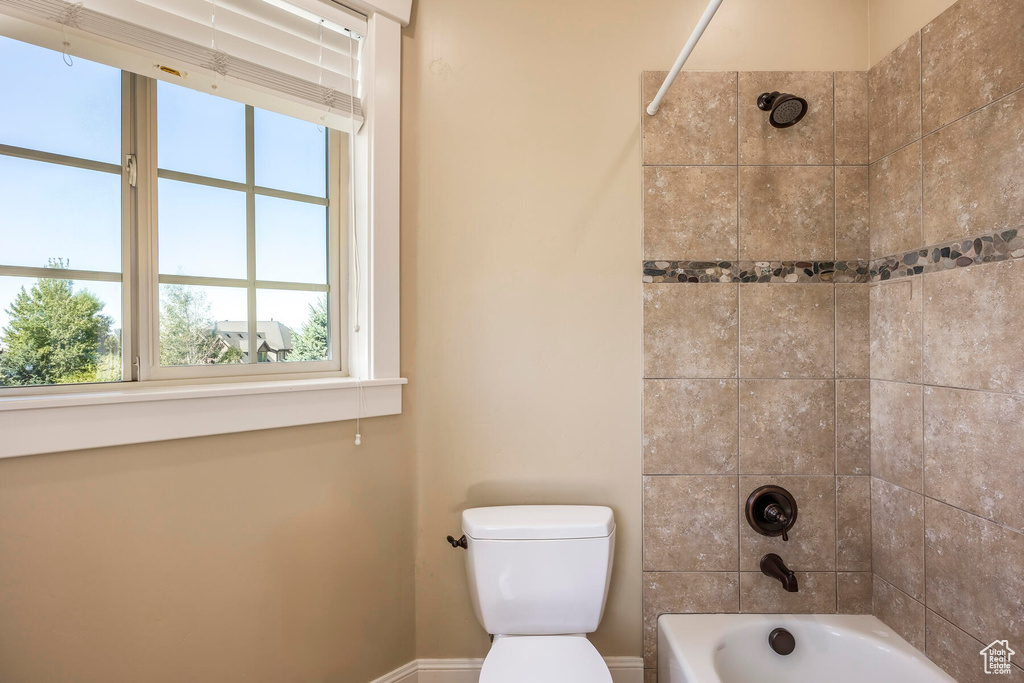 Bathroom featuring tiled shower / bath combo and toilet