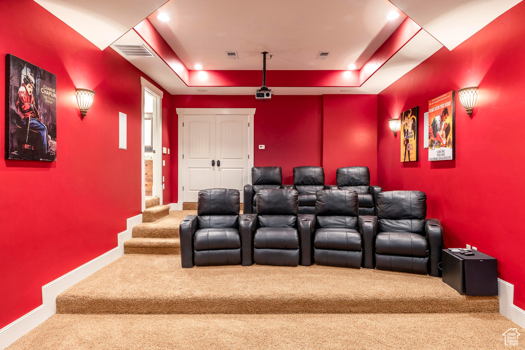 Carpeted home theater room with a tray ceiling