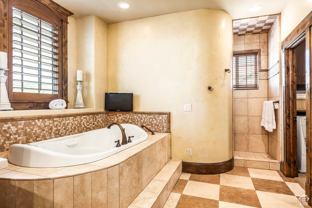 Bathroom featuring tile patterned flooring, tile walls, and plus walk in shower