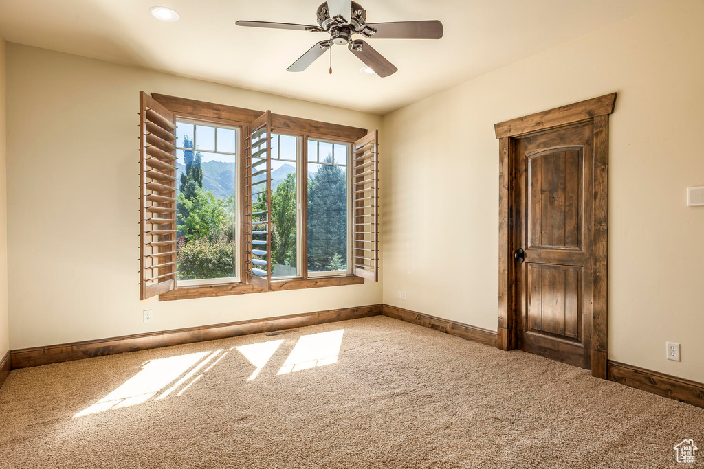 Carpeted empty room featuring ceiling fan