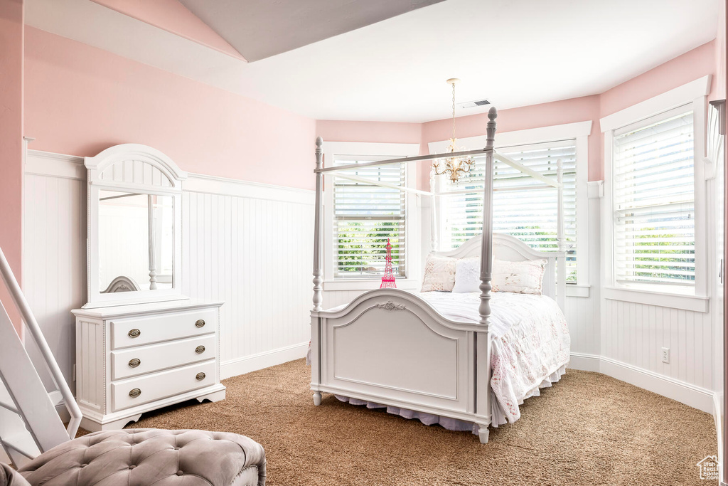 Carpeted bedroom with an inviting chandelier