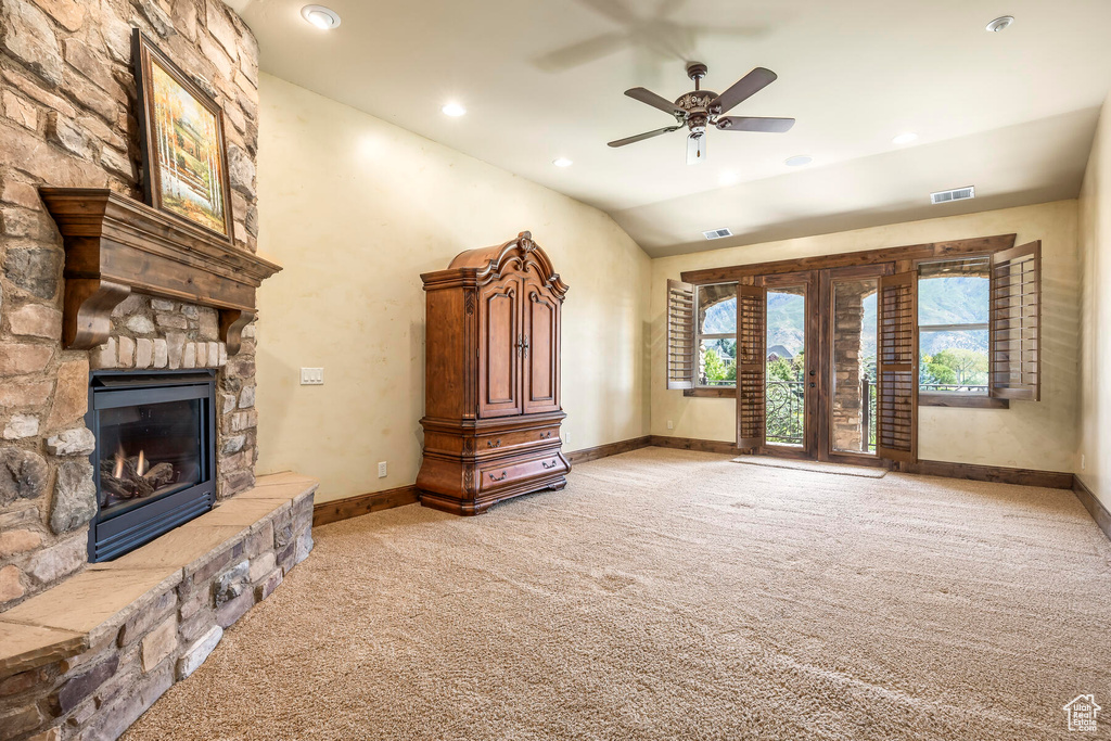 Unfurnished living room with a fireplace, light carpet, vaulted ceiling, and ceiling fan