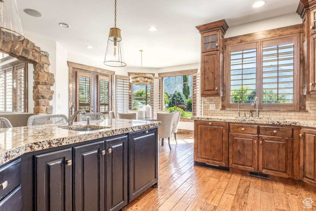 Kitchen featuring light wood-type flooring, sink, decorative backsplash, and pendant lighting