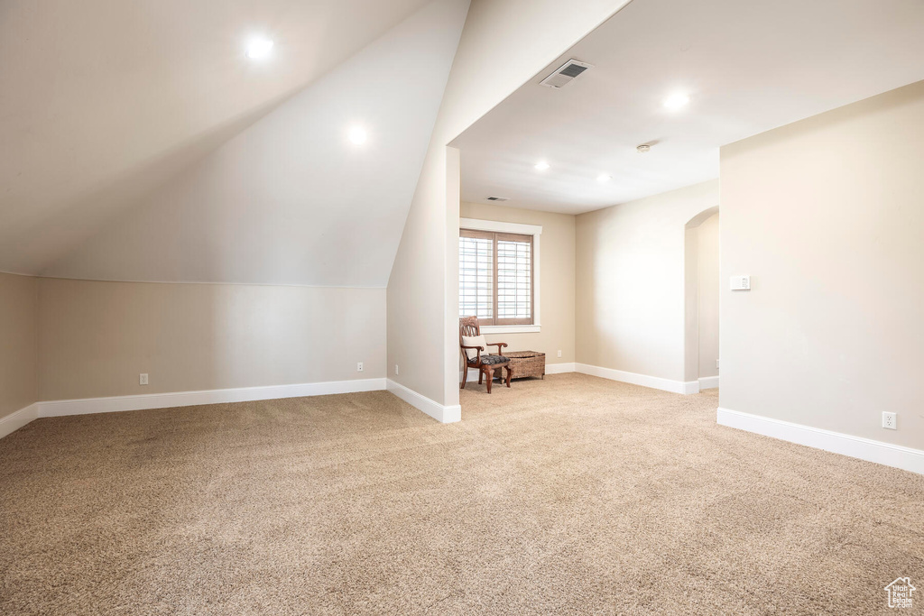 Additional living space featuring vaulted ceiling and light colored carpet