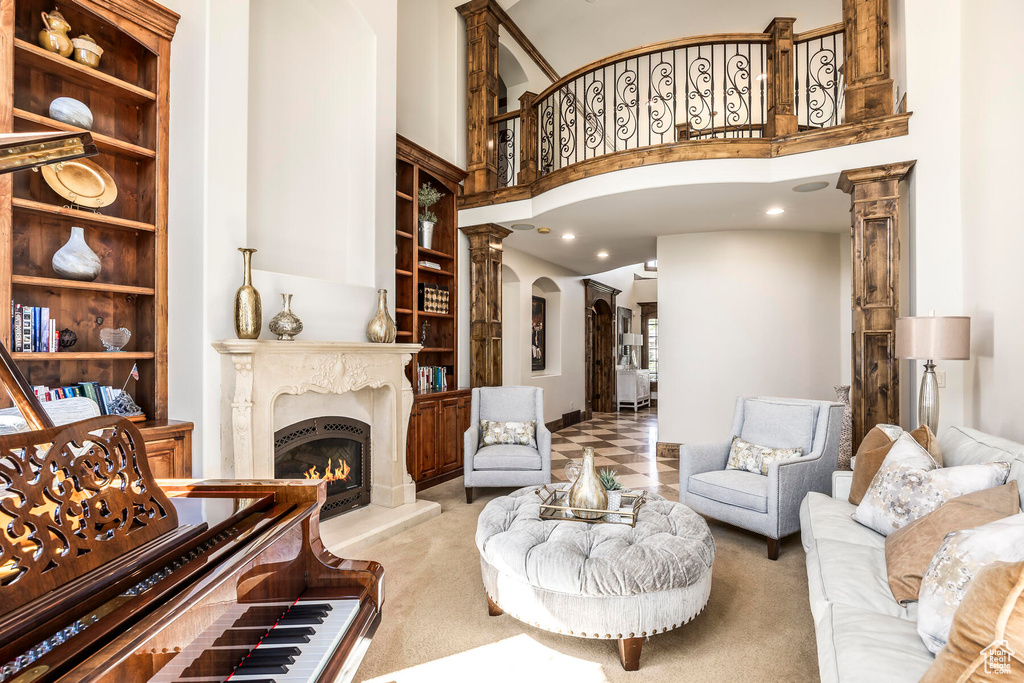 Carpeted living room featuring built in features, ornate columns, and a towering ceiling