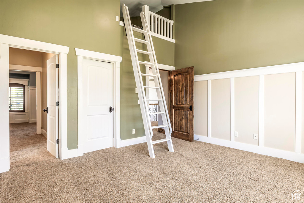 Unfurnished bedroom with a towering ceiling and light carpet