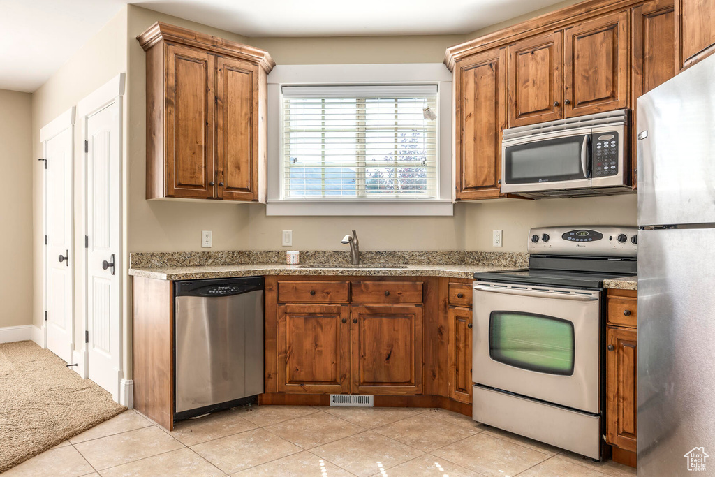 Kitchen with sink, stainless steel appliances, and light stone countertops