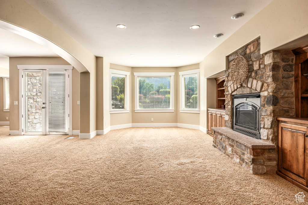 Unfurnished living room featuring carpet floors and a stone fireplace