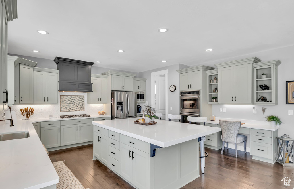 Kitchen featuring appliances with stainless steel finishes, tasteful backsplash, dark hardwood / wood-style floors, and a kitchen island
